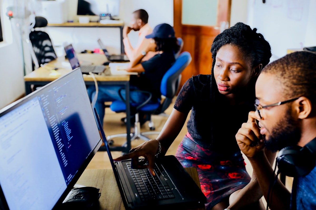 Two colleagues reviewing content strategy on a laptop screen in a modern office
