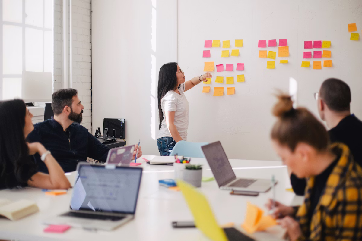 PR team collaborating around a multi-channel planning wall with sticky notes and laptops, representing full-channel stakeholder communications strategy