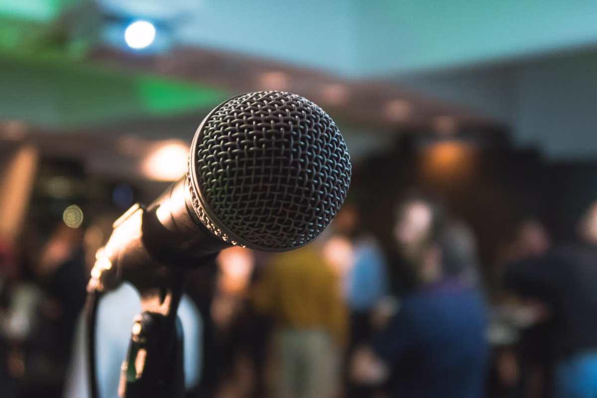Microphone at a live speaking event with an audience in the background, representing executive personal branding and thought leadership