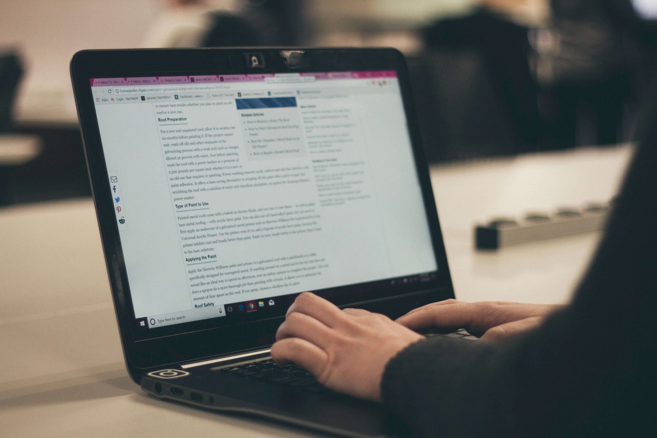 Person typing on a laptop while viewing written digital content on a webpage, representing online product content creation or content management.