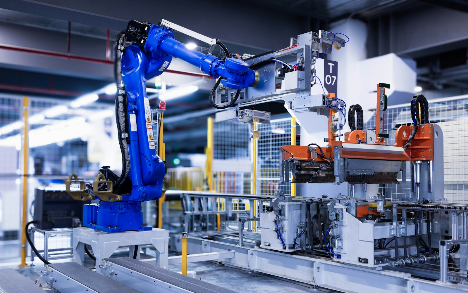 A blue industrial robot arm working on an automated manufacturing production line