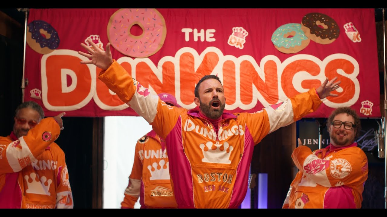 Ben Affleck in an orange and pink DunKings tracksuit with his bandmates in Dunkin's Super Bowl spot